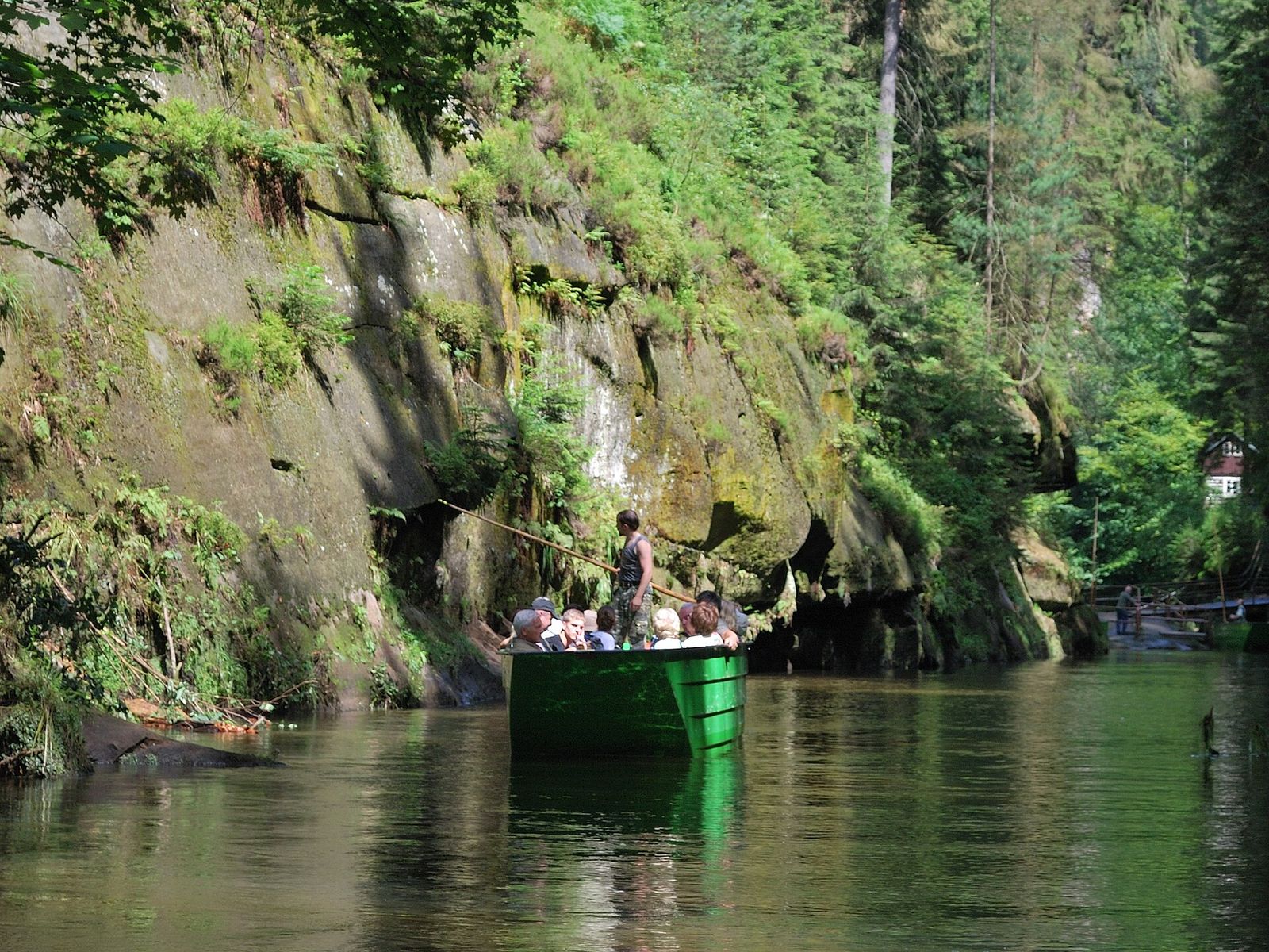 A ferryman punting visitors along the Kamenice river below steep rock walls in Edmund's Gorge